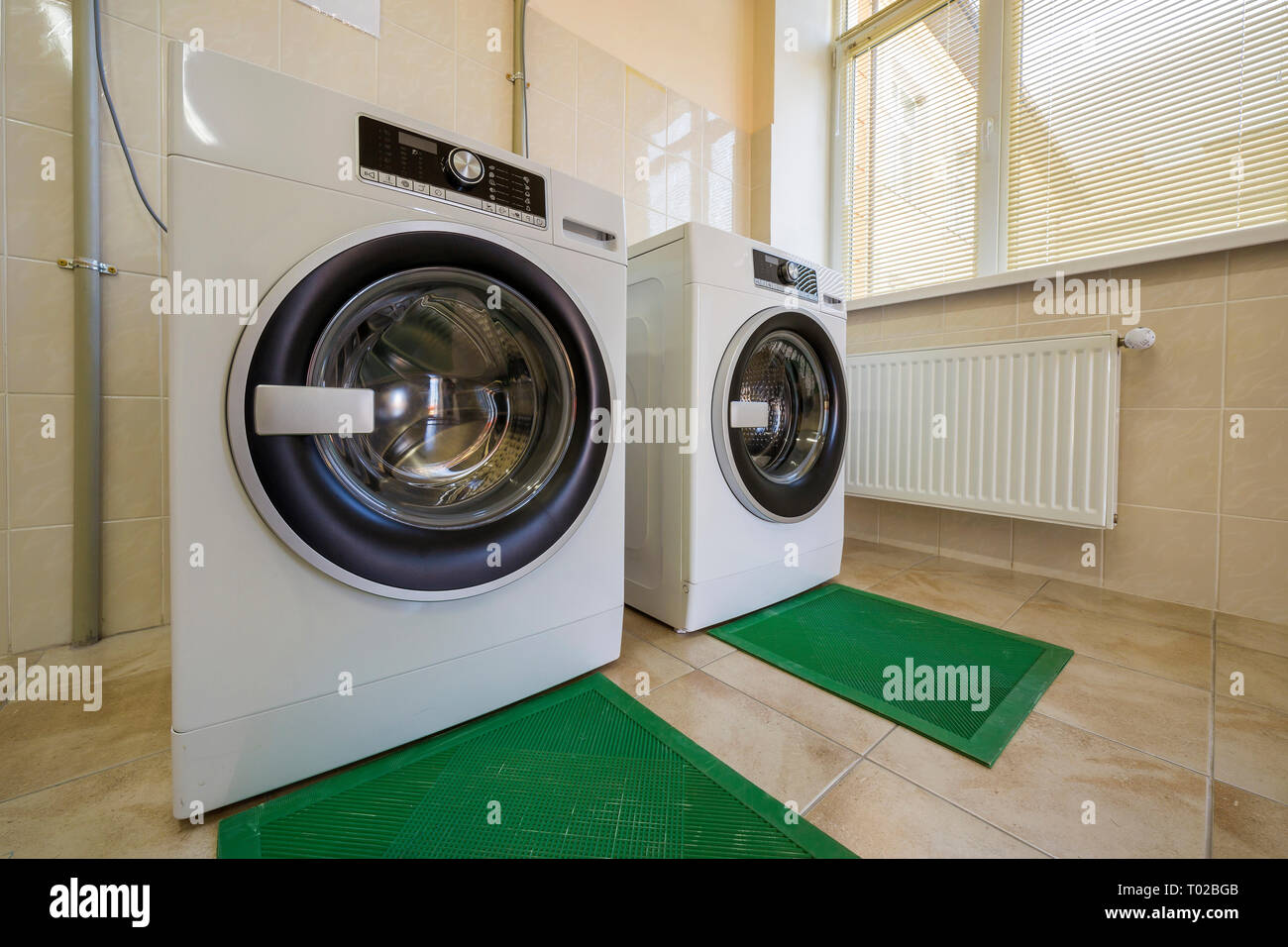 Modern New Industrial Washing Machines In Clean Tiled Bathroom Or