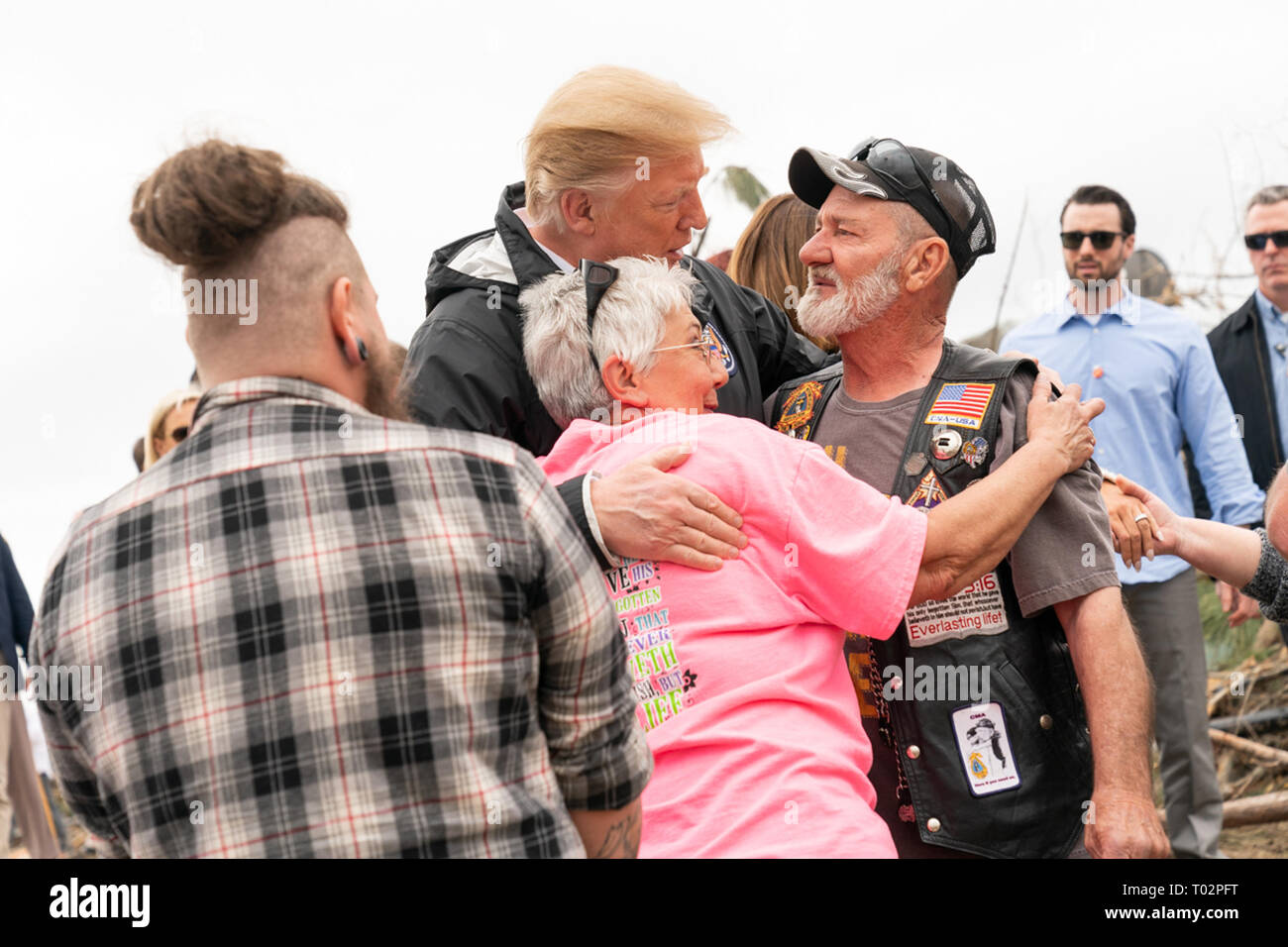 President Donald J. Trump is embraced by residents Friday, March 8, 2019, as he visits a neighborhood devastated by a tornado that touched down Sunday in Lee County, Ala.  People:  President Donald Trump Stock Photo