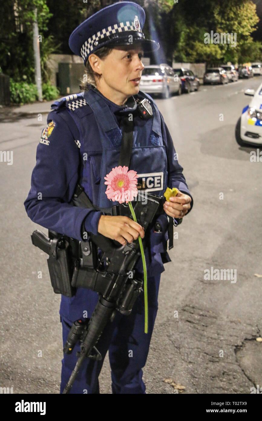 Christchurch, New Zealand. 16th March 2019. Police officer stands guarding the mosque shooting cordon with a pistol, automatic rifle, bullet proof vest and a flower after the Christchurch mosques shooting. Around 50 people has been reportedly killed in the Christchurch mosques terrorist attack shooting targeting the Masjid Al Noor Mosque and the Linwood Mosque. Credit: SOPA Images Limited/Alamy Live News Stock Photo