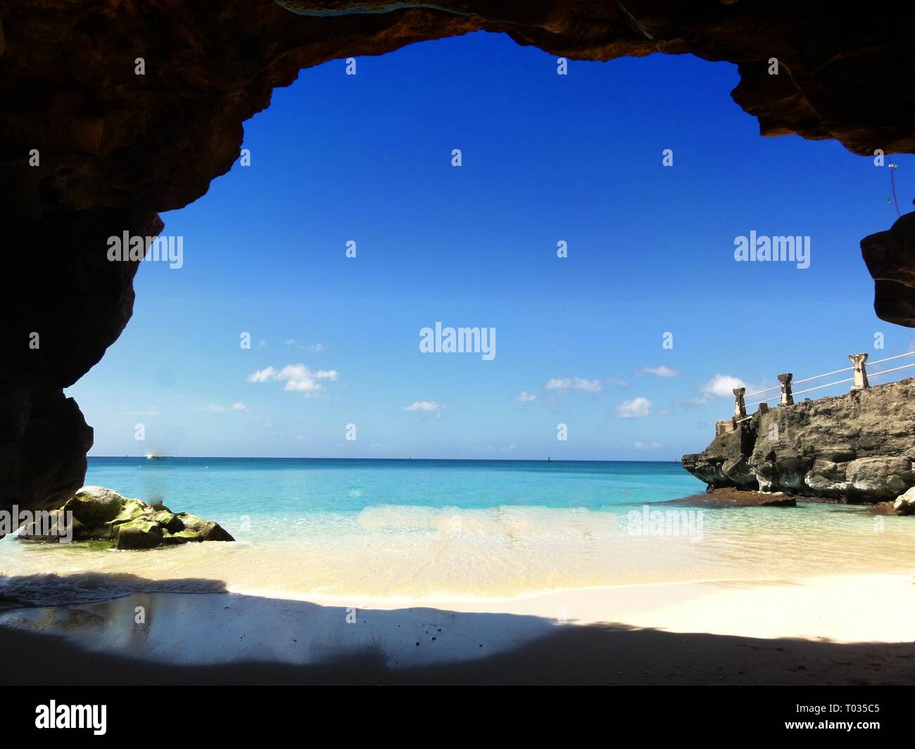 Pristine beach and clear blue waters of Taga Beach   Tinian, the Northern Mariana Islands, seen from the shelter of a rocky cave Stock Photo