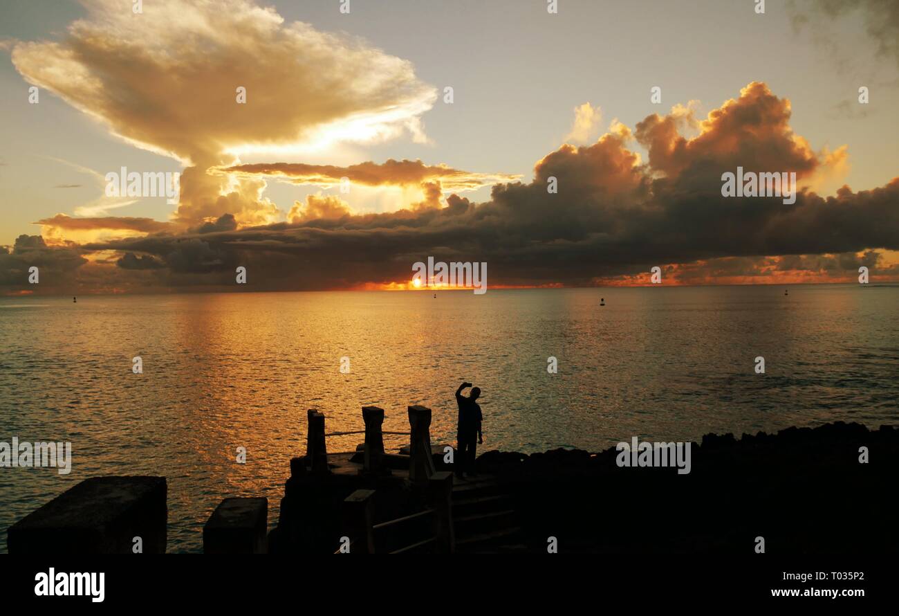 Breathtaking clouds at sunset reflected in the waters of Taga Beach, Tinian, Northern Mariana Islands Stock Photo