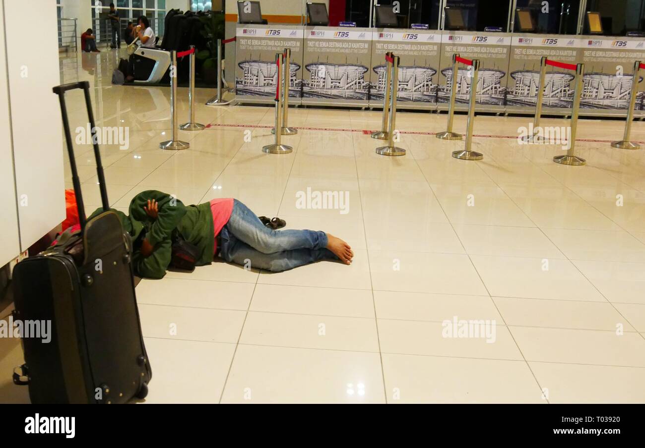KUALA LUMPUR, MALAYSIA—MARCH 2016: A female passenger sleeps barefoot on the shiny floors of the Terminal Bersepadu Selatan at Bandar Tasik Stock Photo