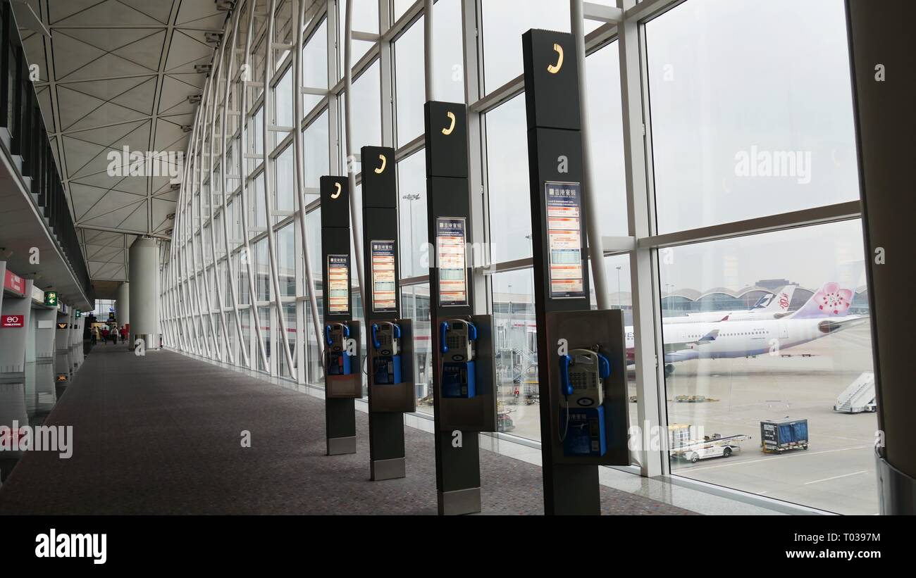 HONG KONG—DECEMBER 2016: Row of telephones mounted on columns at the Hong Kong International Airport pre-departure areas. Stock Photo