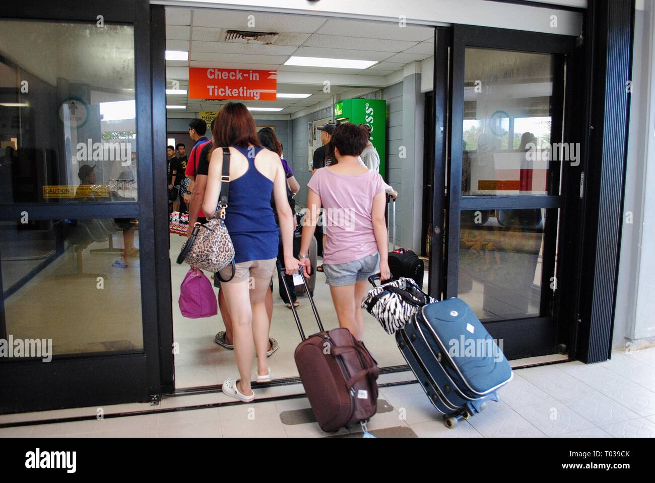 TINIAN, CNMI, USA—OCTOBER 2016: Passengers pulling luggage into the check-in and ticketing area at the Tinian International Airport. Stock Photo
