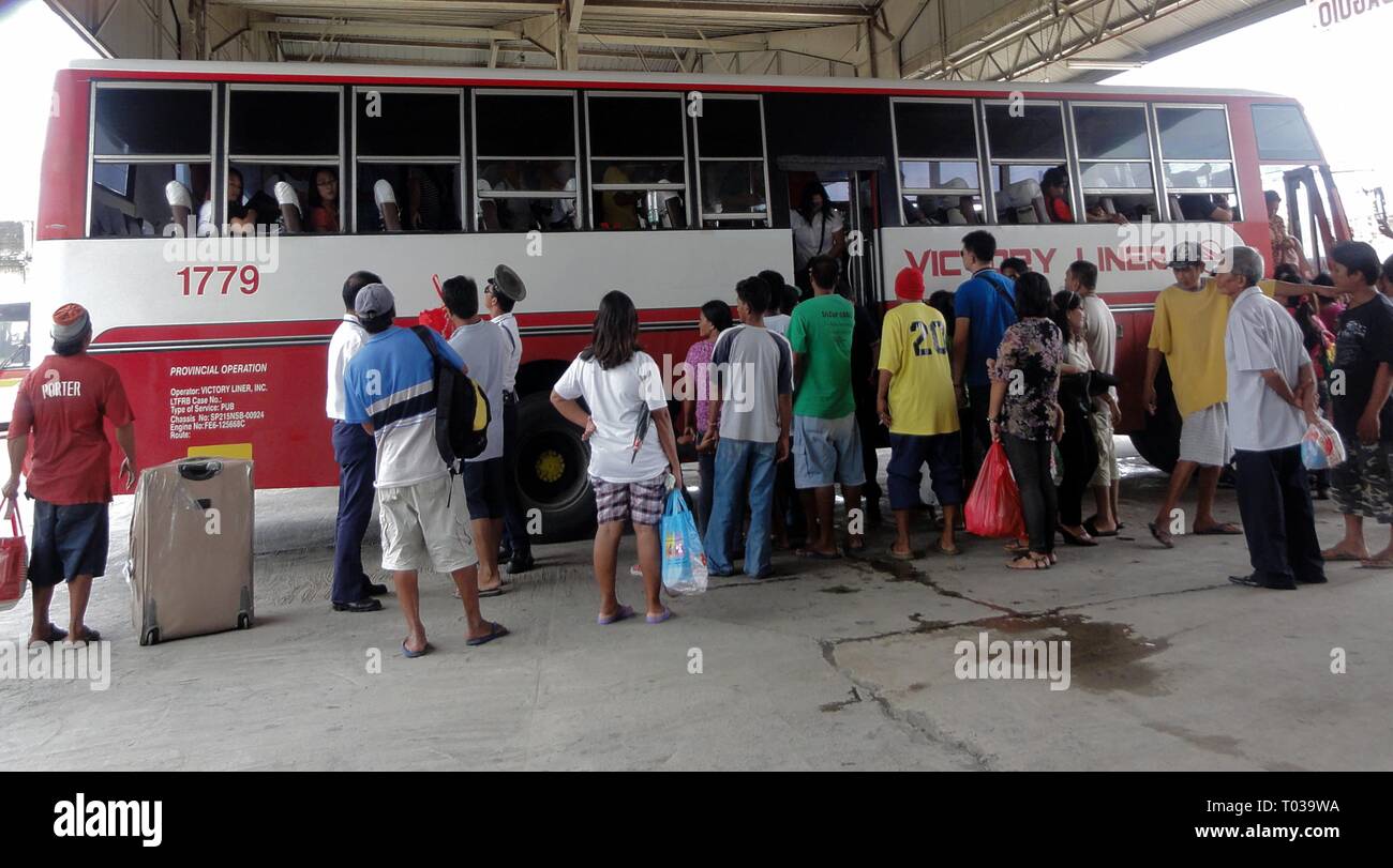 ALAMINOS, PANGASINAN, PHILIPPINES—AUGUST 2014: Passengers pressing to board a Victory Liner bus at the Alaminos City bus terminal. Stock Photo