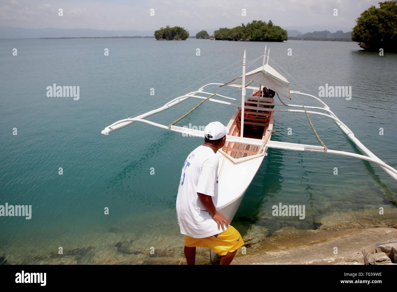 SURIGAO DEL SUR,PHILIPPINES—A fisherman pulls his boat ready to go out at the clear waters of Cantilan in Surigao del Sur in August 2014. Stock Photo