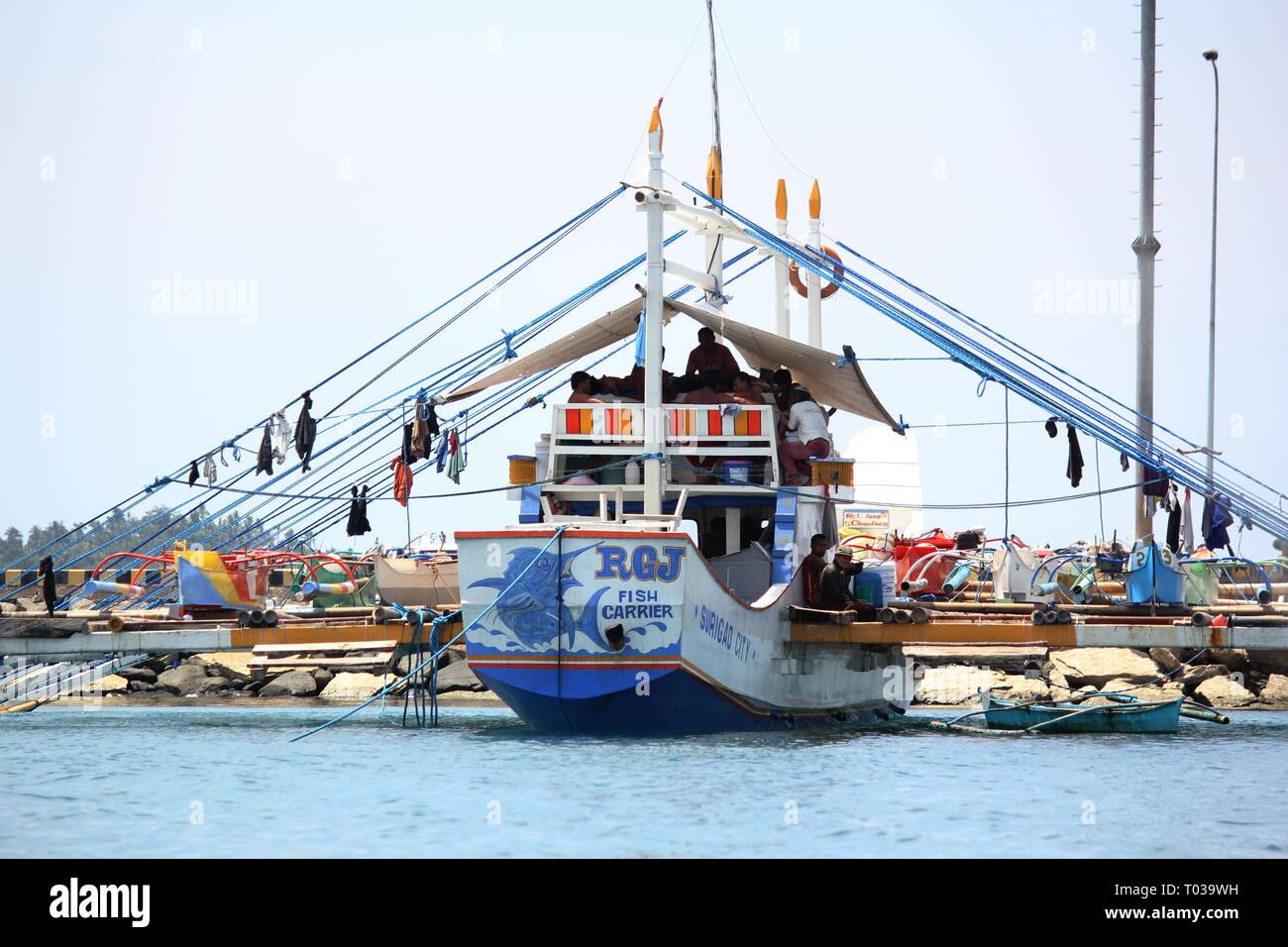 SURIGAO DEL SUR, PHILIPPINES—AUGUST 2014: A fishing boat with fishermen resting docked at Cantilan in Surigao del Sur, southern Philippines. Stock Photo