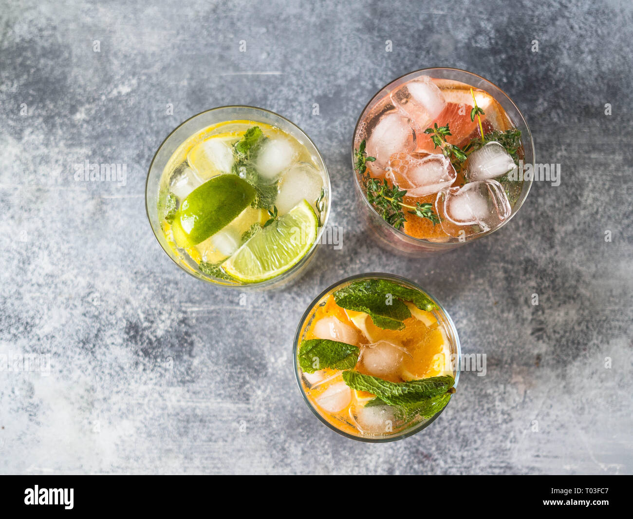Set summer cold drinks with different citrus in glasses on a gray background. Cocktail with grapefruit, orange, lemon lime and ice Stock Photo
