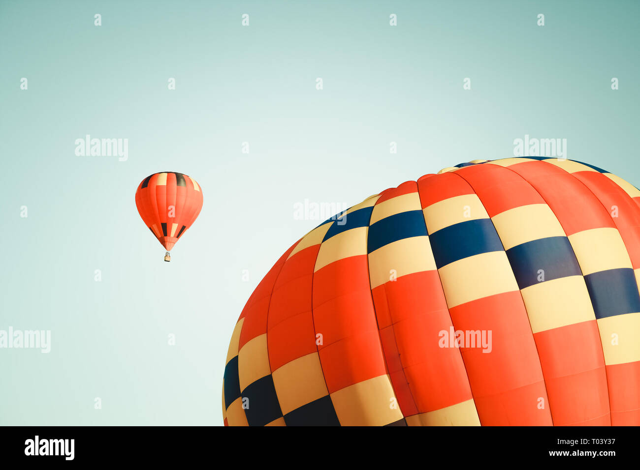 Two vibrant hot air balloons in clear sky, one close and one far. Stock Photo