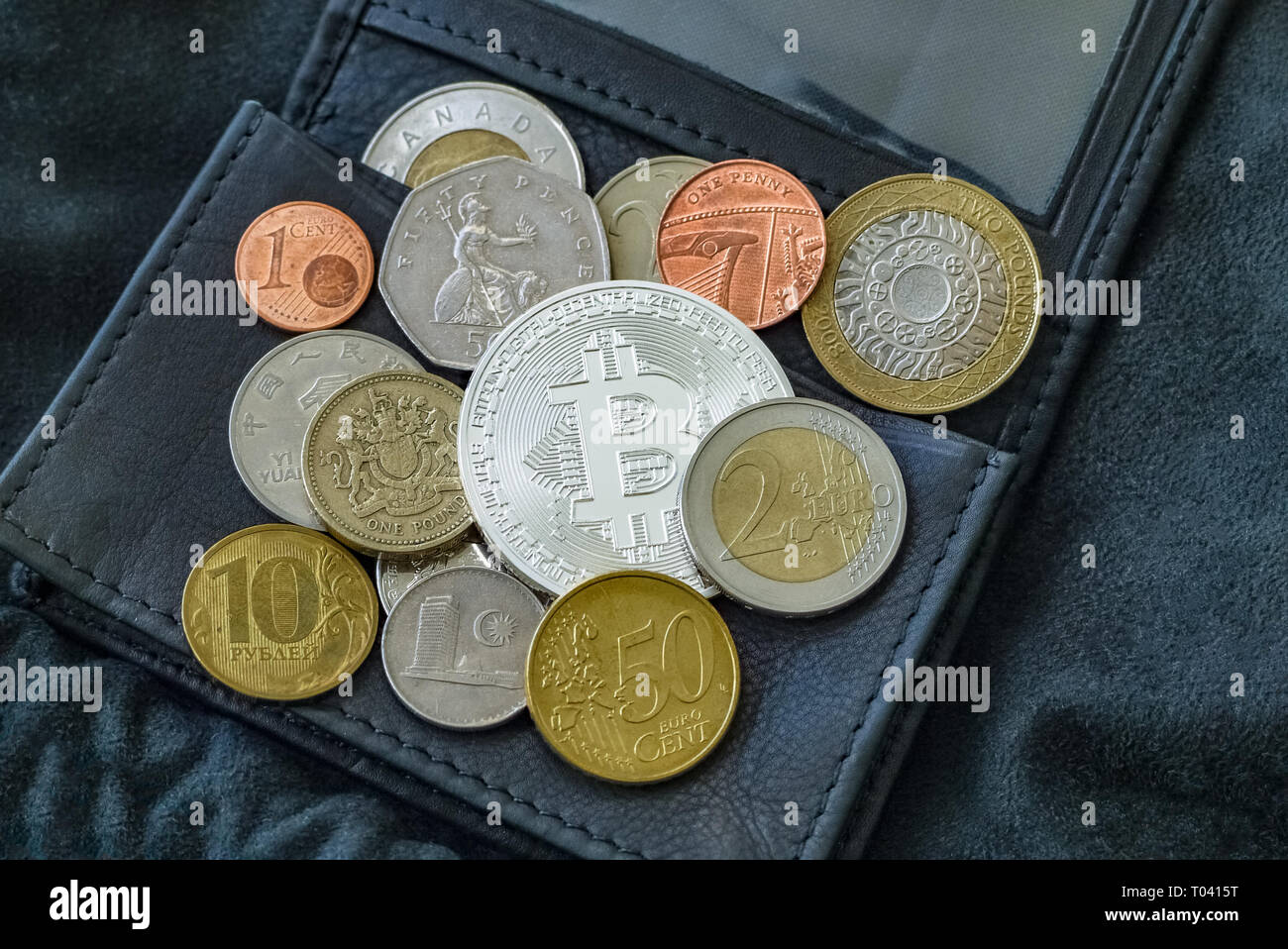 Bitcoin, national and euro coins on black leather wallet. Stock Photo