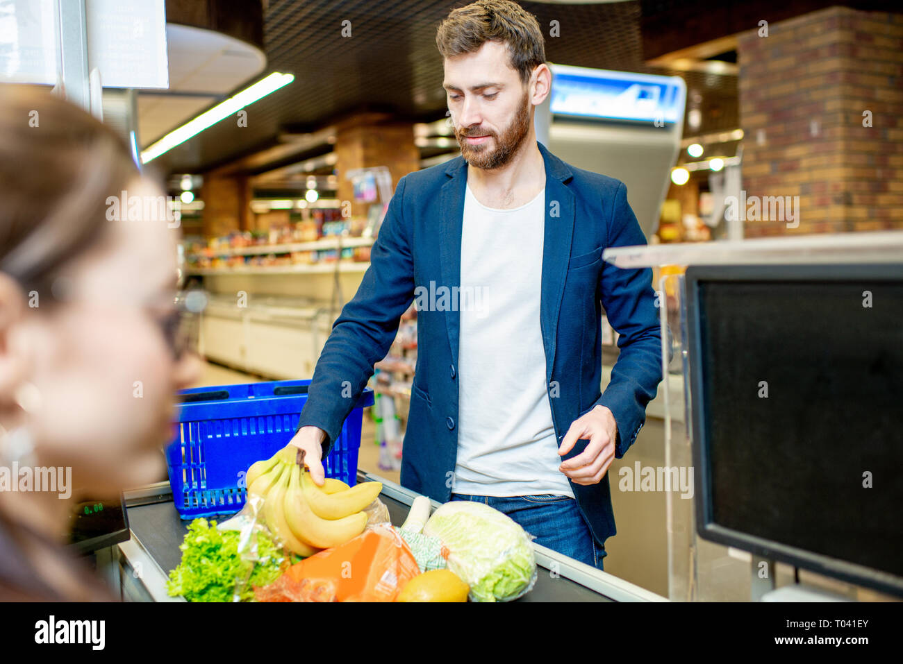 Handsome businessman putting products on the cash register buying food in the supermarket Stock Photo