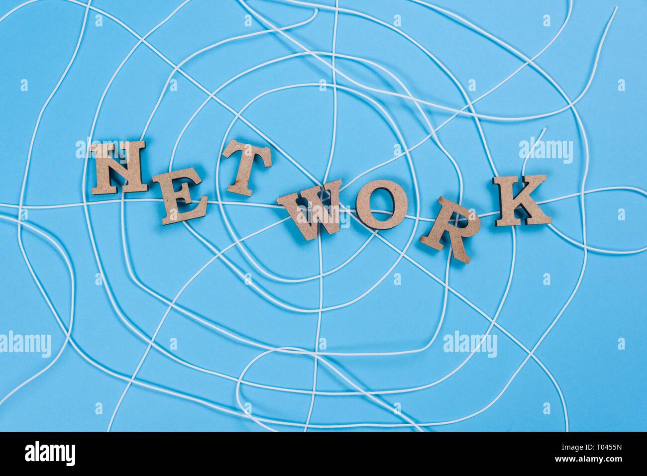 The word network with wooden letters in the form of an abstract spider web, blue background. Stock Photo