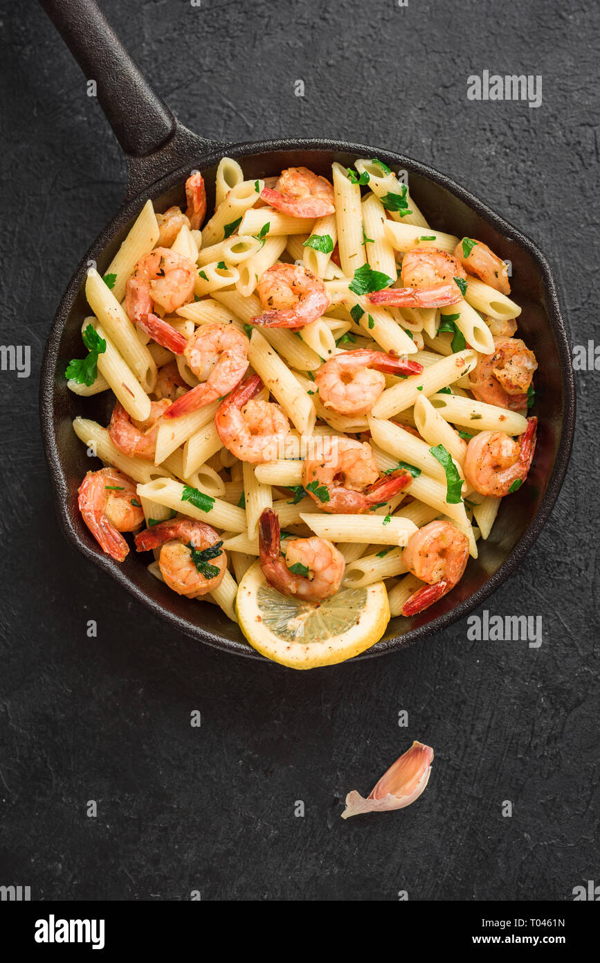 Penne Pasta with Prawns or Shrimps on black, top view, copy space. Lemon pasta with sauteed shrimps, fresh seafood. Stock Photo