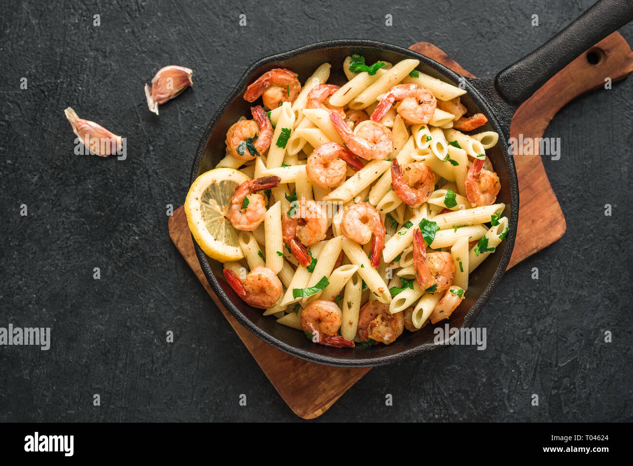 Penne Pasta with Prawns or Shrimps on black, top view, copy space. Lemon pasta with sauteed shrimps, fresh seafood. Stock Photo
