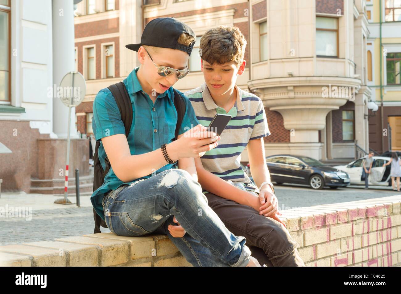 The friendship and communication of two teenage boys is 13, 14 years old, city street background. Stock Photo