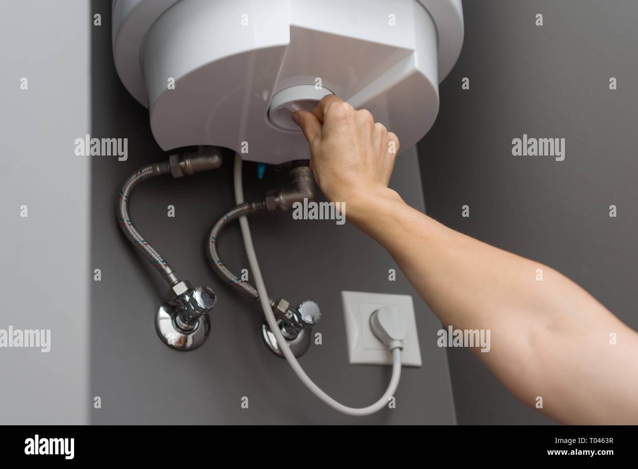 Woman hands setting temperature of water in heater electric boiler