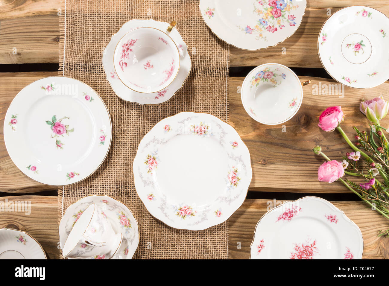 Old romantic porcelain, pink flowers arranged on rustic wood planks. Shot from above, flat lay. Stock Photo