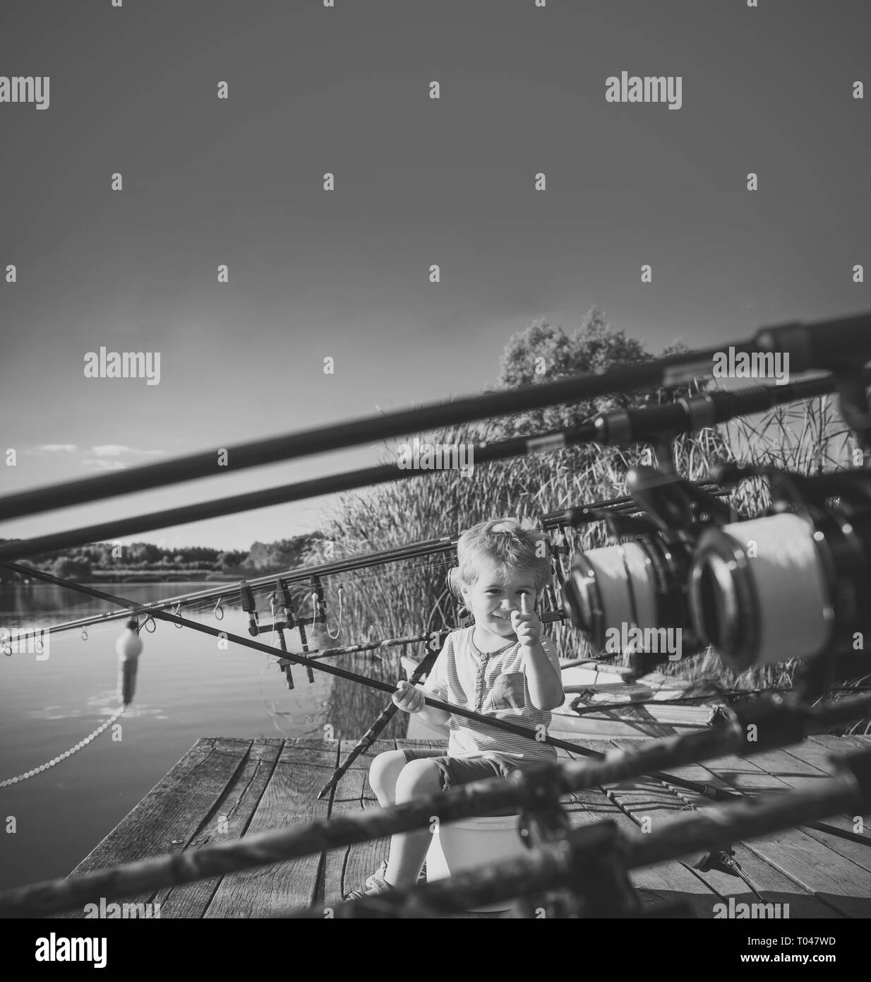 Picturesque scene of cute little boy fishing from wooden dock Stock Photo