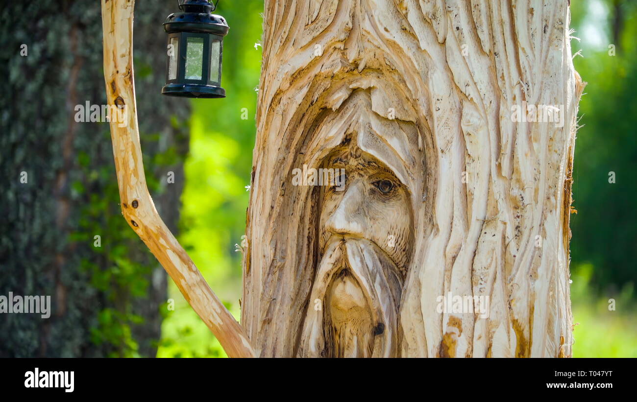 An image being carved on the trunk of a wooden tree a nice statue for decorations with a hanging lamp on the side Stock Photo