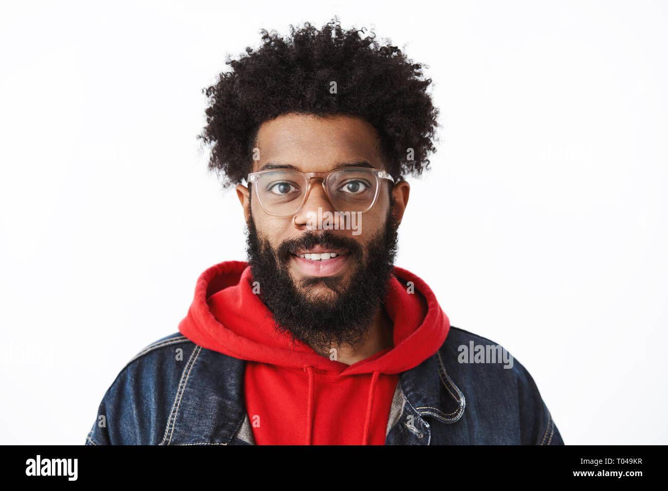 Headshot of ambitious and handsome young creative african american freelancer with pierced nose and afro hairstyle in glasses smiling joyfully at Stock Photo