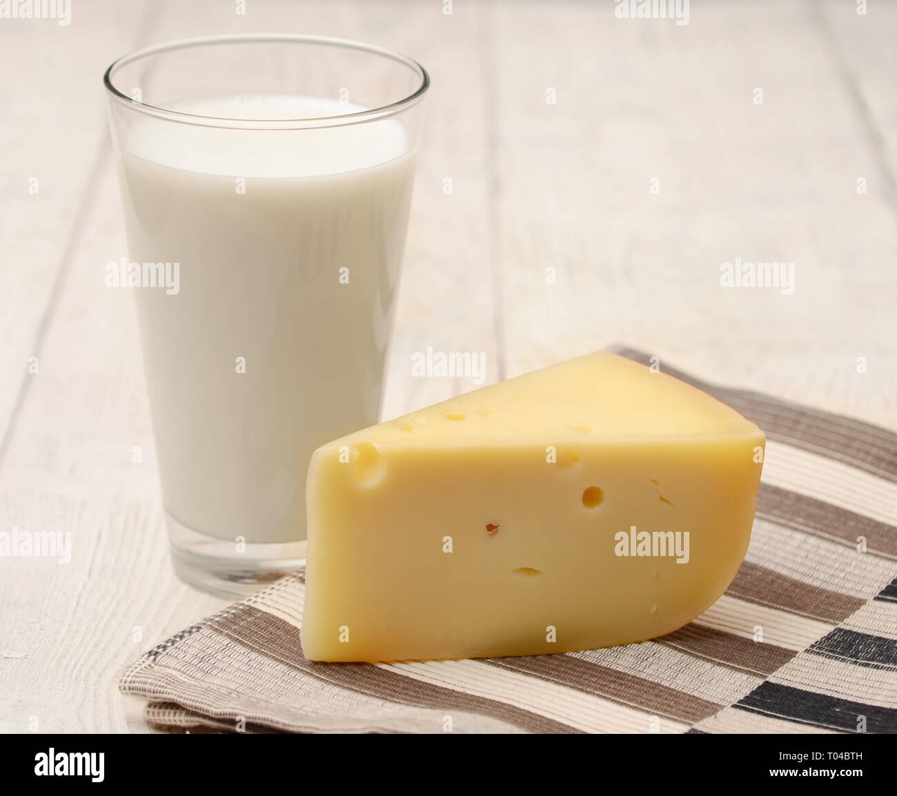 A glass of milk and a piece of cheese on the old table Stock Photo