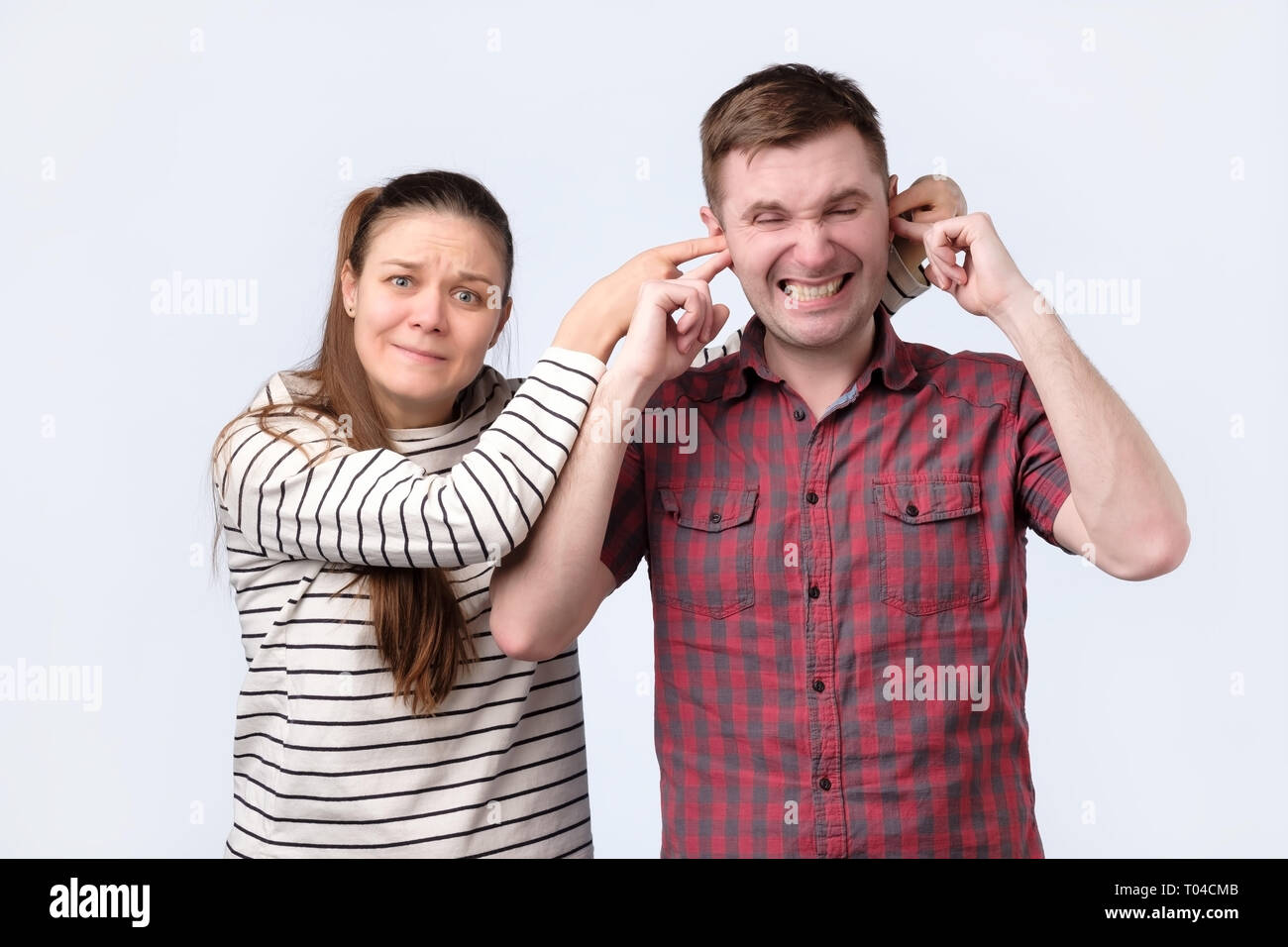 woman closing her husband ears. she wants to keep something in secret. Stock Photo
