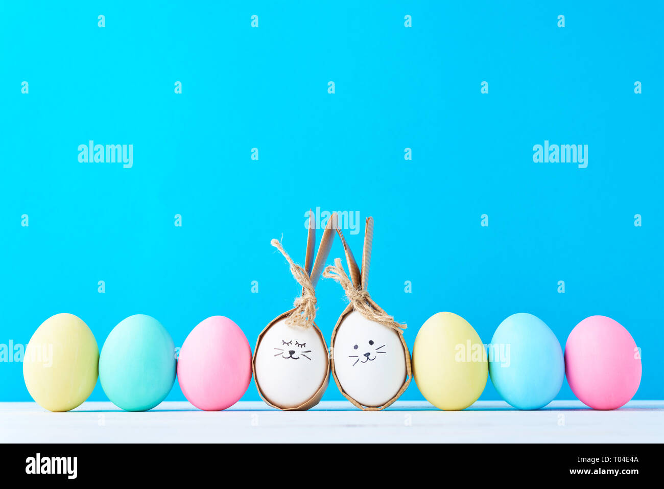Easter eggs with painted faces in row on blue background Stock Photo