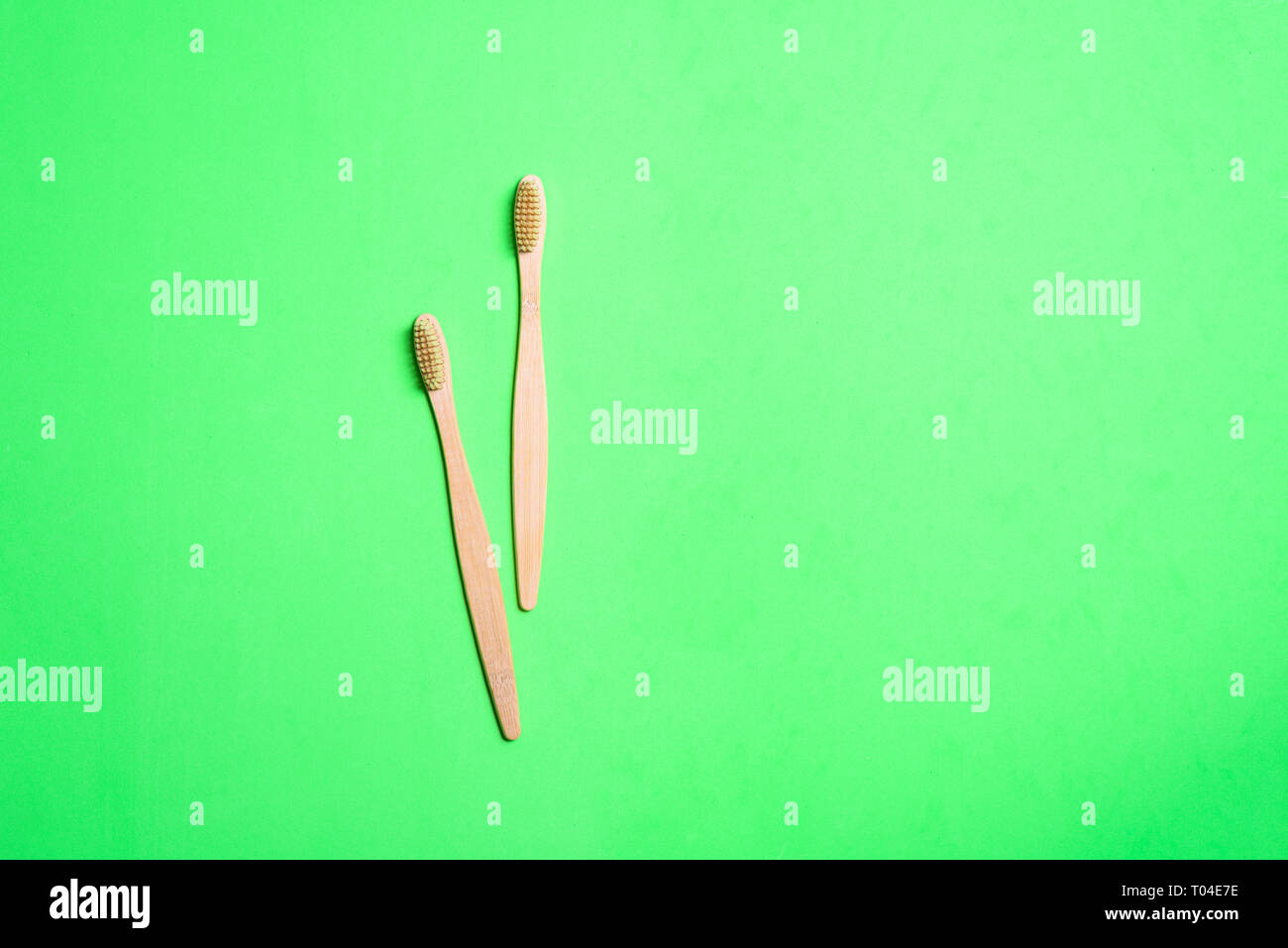 Two wooden toothbrushes on light green background Stock Photo