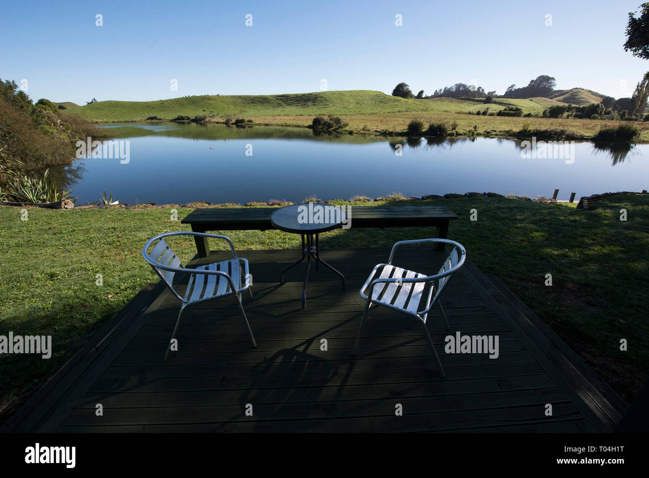 Lakeside view, Verandah with table and chairs by lake, Lake Farm, Taranaki, North Island, New Zealand Stock Photo