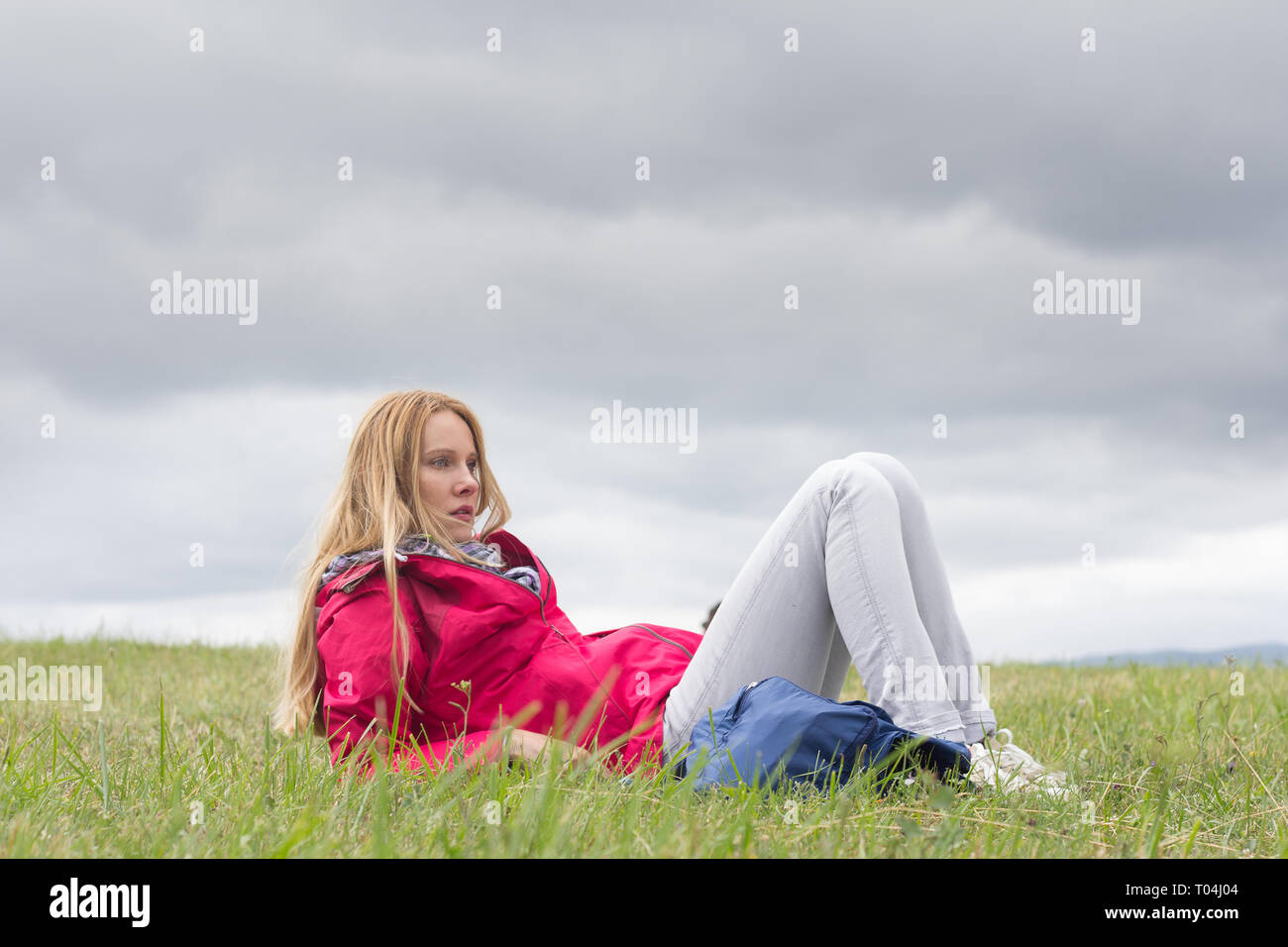 young woman sitting alone on meadow Stock Photo