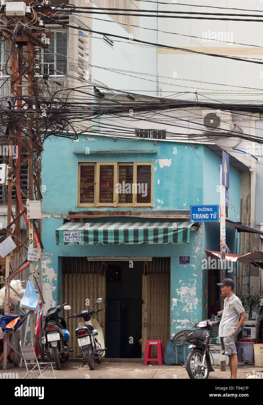 man standing near weathered house facade on street in Vietnam Stock Photo