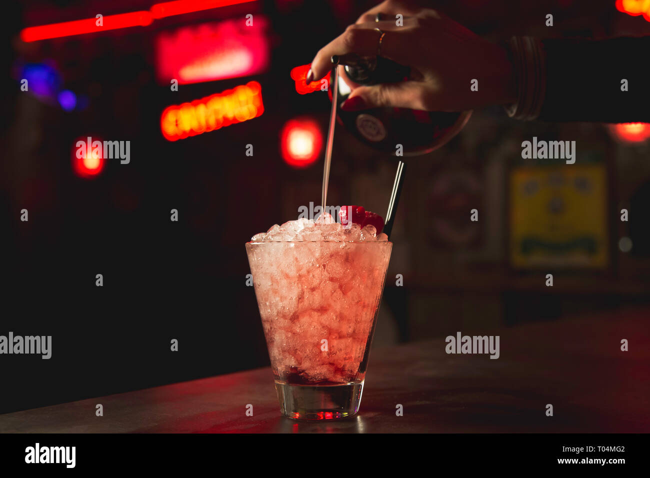 Woman's hand pouring raspberry cocktail over crushed ice Stock Photo