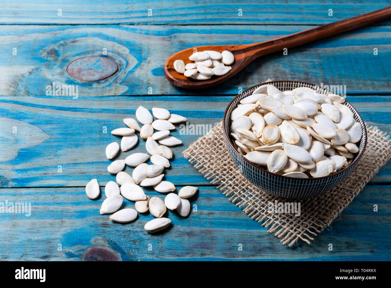 Pumpkin seed inside ceramic pot over blue pine wood. Stock Photo