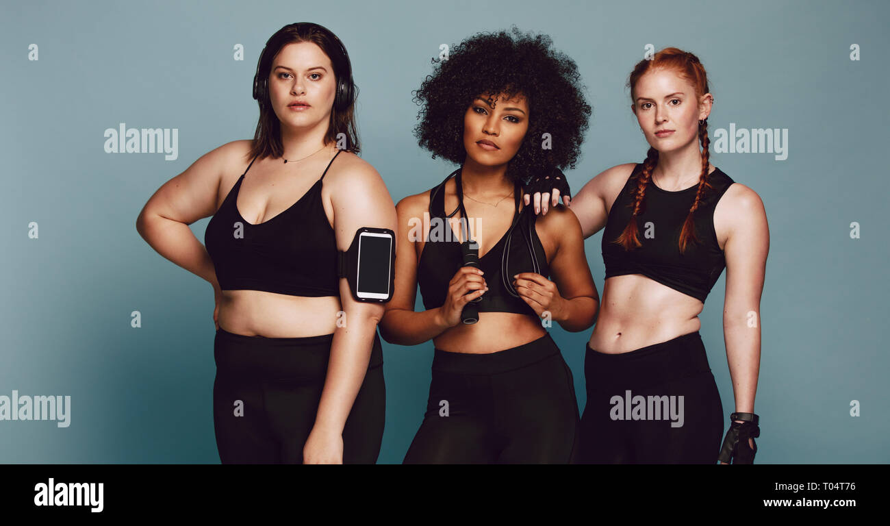 Group of women of different race, figure type and size dressed in sportswear  standing together against grey background. Three diverse women in sports  Stock Photo - Alamy