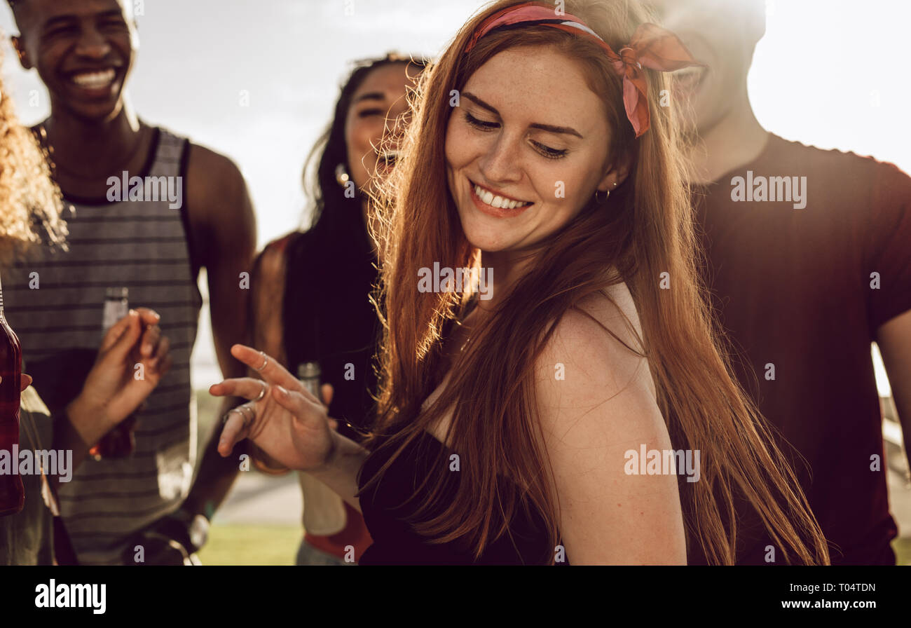 Beautiful woman dancing with friends around outdoors. Woman having a great time with group of friends on summer day. Stock Photo