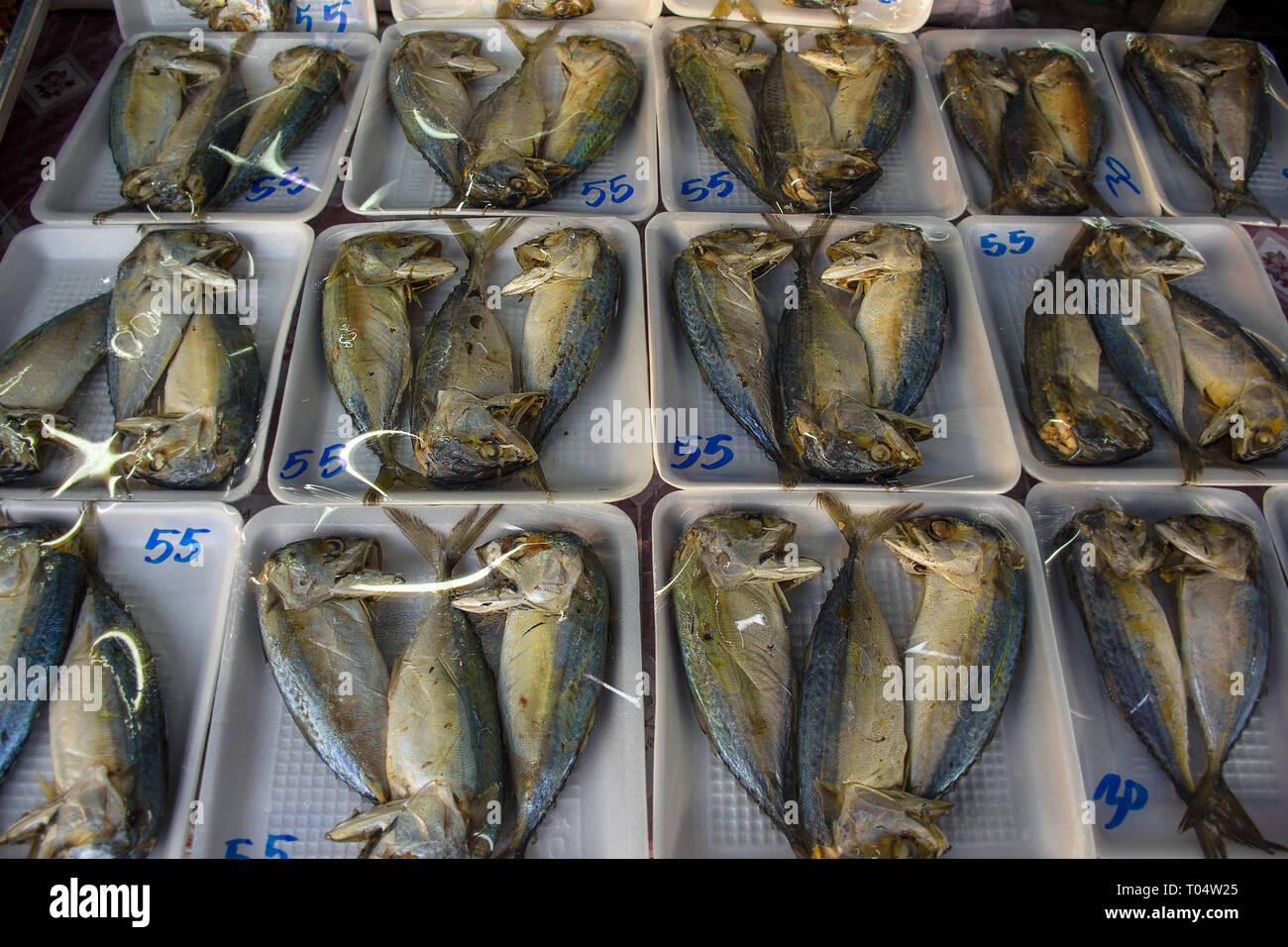 Dried fish packaged and on display for sale on a market stall. Stock Photo
