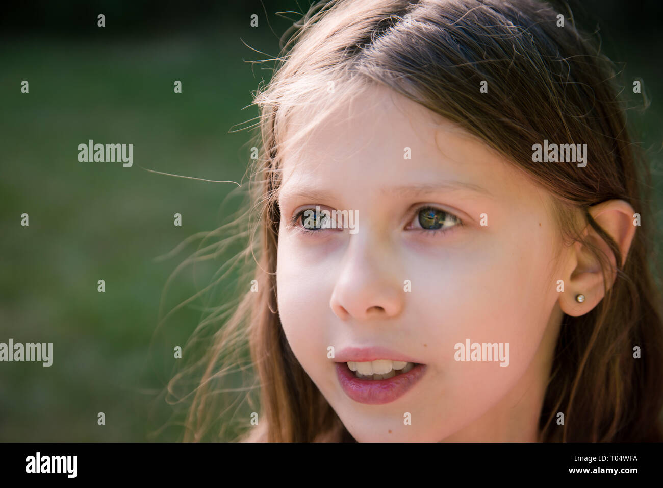 Close-up portrait of face of caucasian girl child outside, gazing into the distance deep in thought Stock Photo