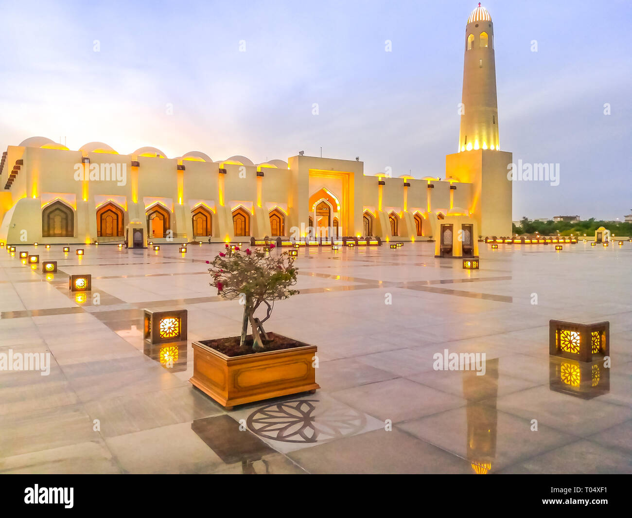 Wide view of Doha Grand Mosque illuminated, mirroring on outdoor marble pavement. Qatar State Mosque, Middle East, Arabian Peninsula in Persian Gulf Stock Photo
