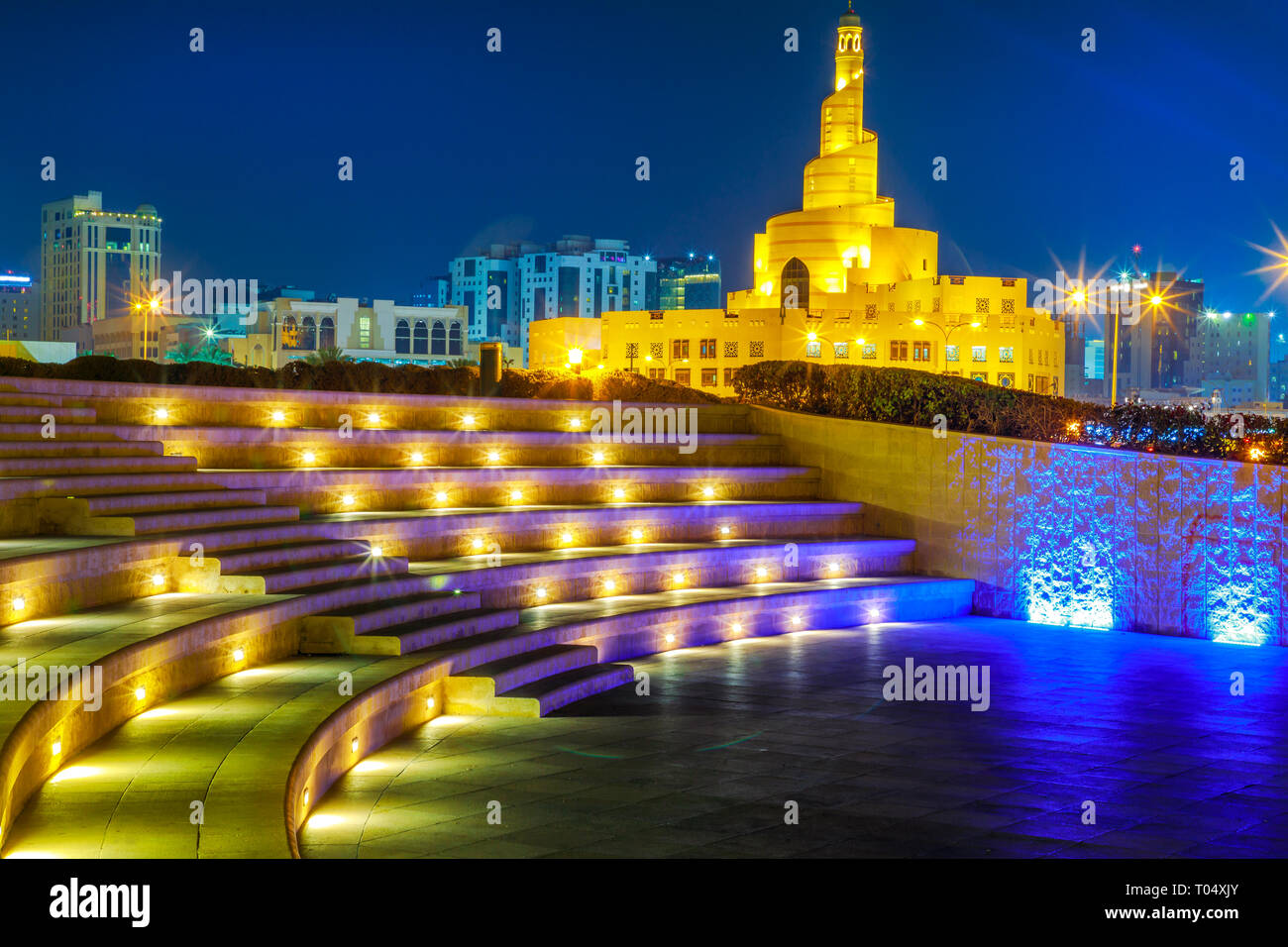 Stairs of small amphitheater at Souq Waqif Garden near Doha Corniche with Doha mosque at night. Doha city center in Qatar, Middle East, Arabian Stock Photo