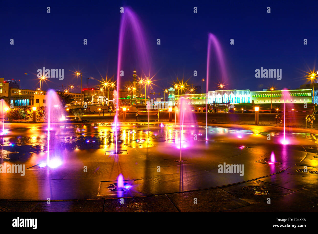 Colorful water fountain at Souq Waqif Park at Doha Corniche with Al shaykh Mosque illuminated at night on background. Doha city center in Qatar Stock Photo