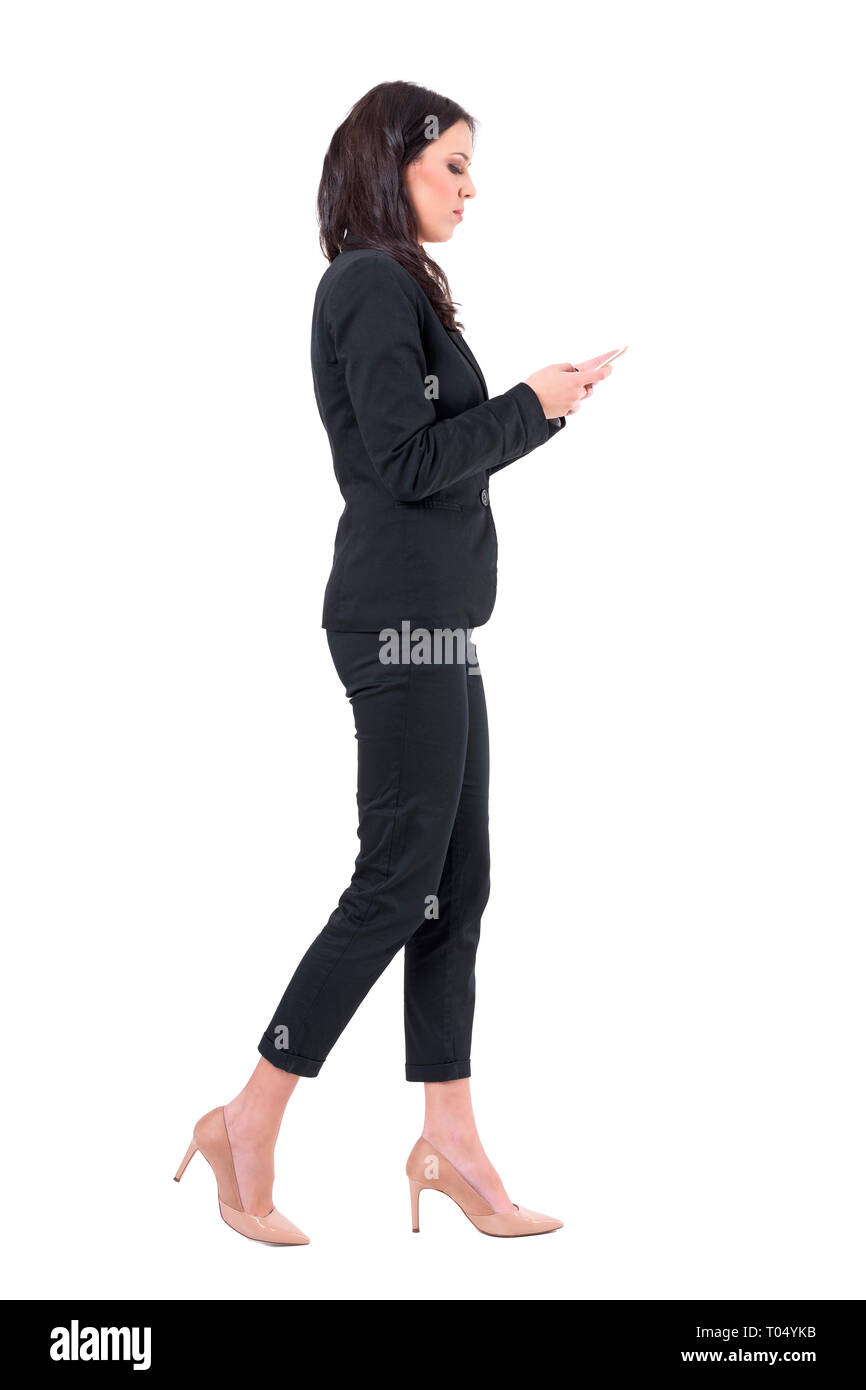 Busy business woman multitasking walking and reading messages on mobile phone. Full body isolated on white background. Stock Photo