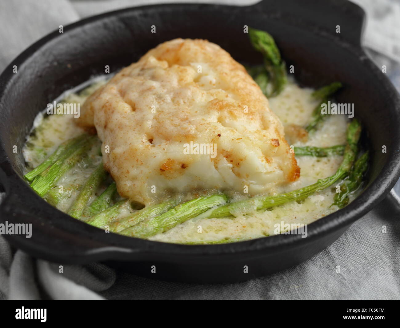 Baked haddock fish with asparagus under cream sauce Stock Photo Alamy