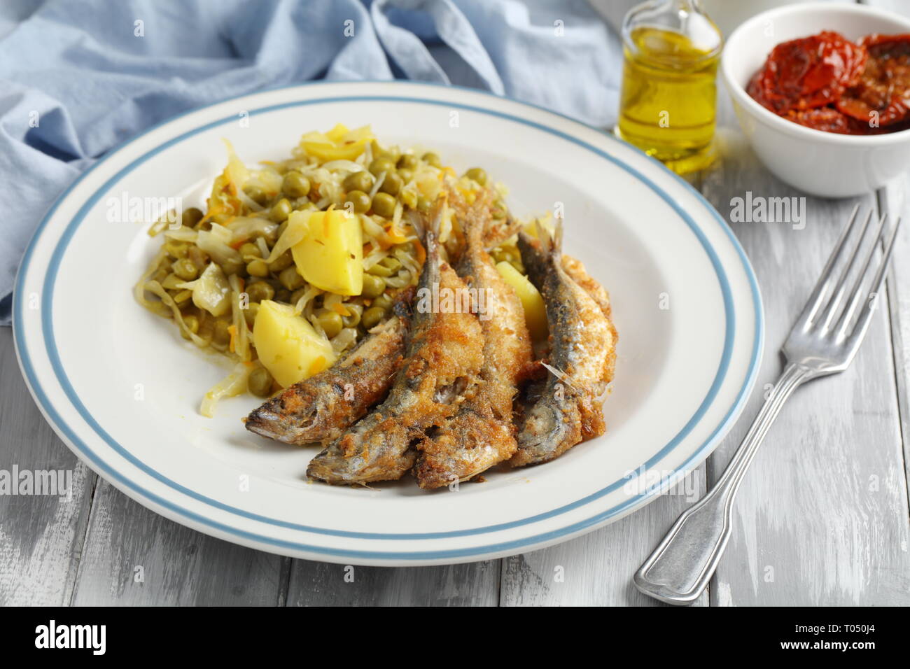 Chicharros fritos, traditional Portugal roasted breaded horse mackerel fishes with cabbage, potato, and green pea stew Stock Photo