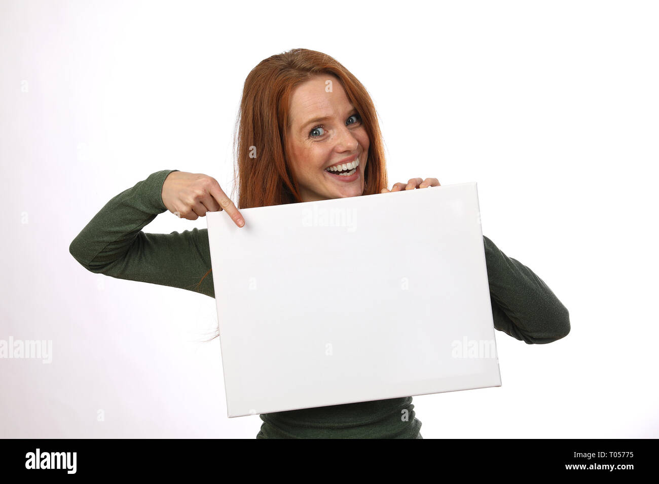Beautiful red haired woman smiles while pointing on a sign Stock Photo ...