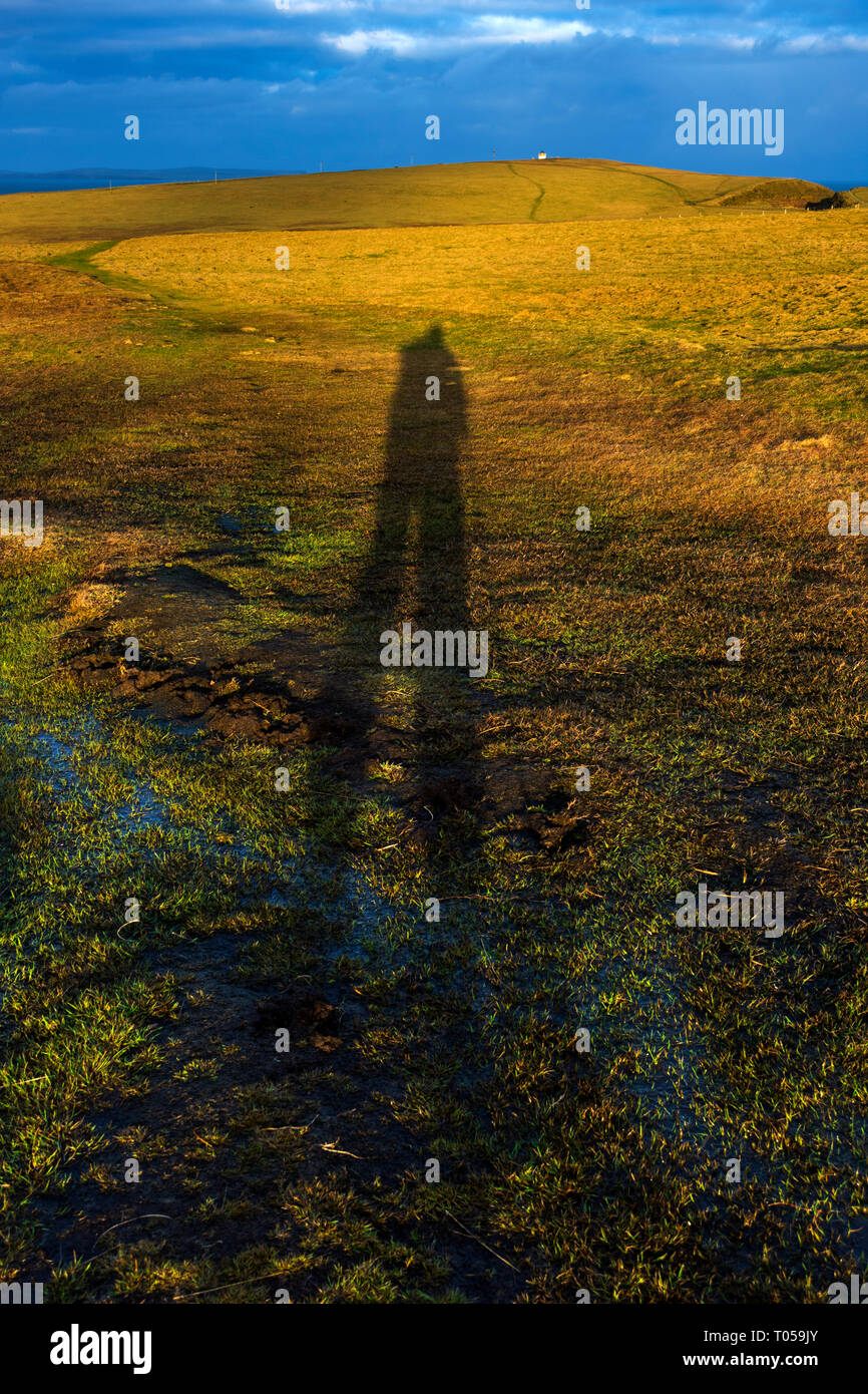 Shadow of a walker pointing towards the lighthouse on Duncansby Head, Caithness, Scotland, UK Stock Photo