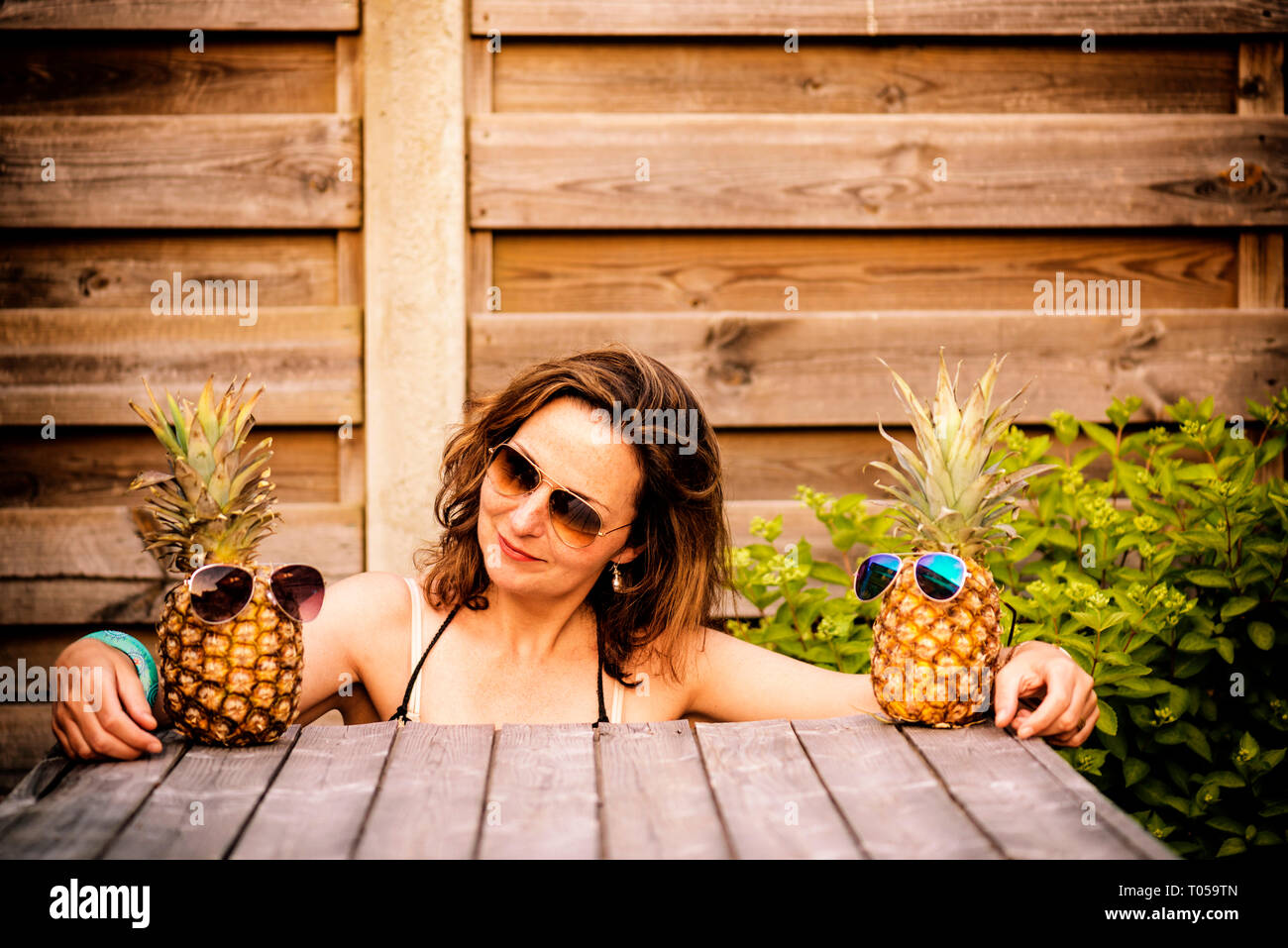 woman between two pineapples wearing sunglasses, as if she's between her best friends Stock Photo