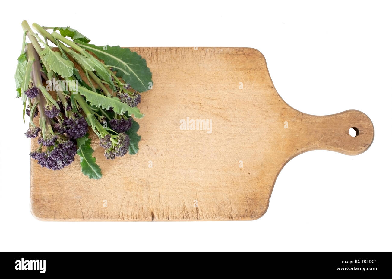 Early purple sprouting broccoli spring vegetable, with wooden food cutting board. Isolated on white. Overhead view. Stock Photo