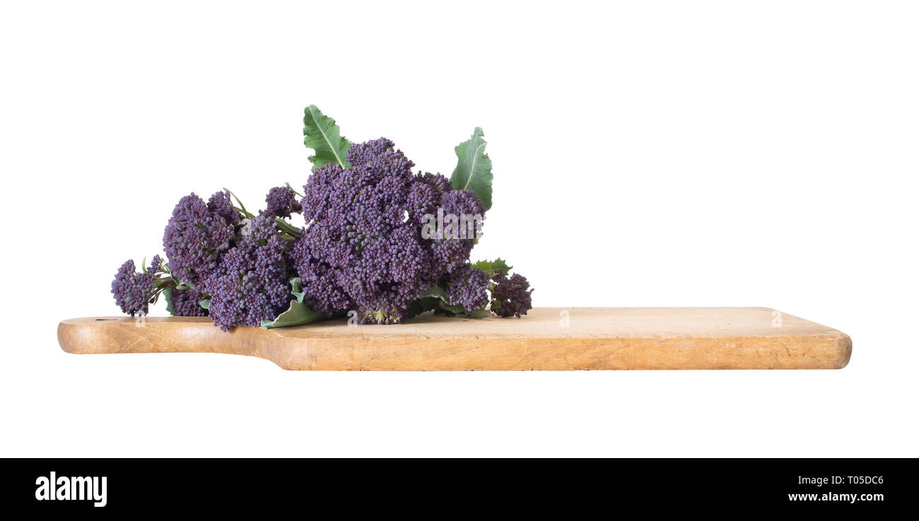 Early purple sprouting broccoli spring vegetable, with wooden food cutting board. Isolated on white. Low angle view. Stock Photo