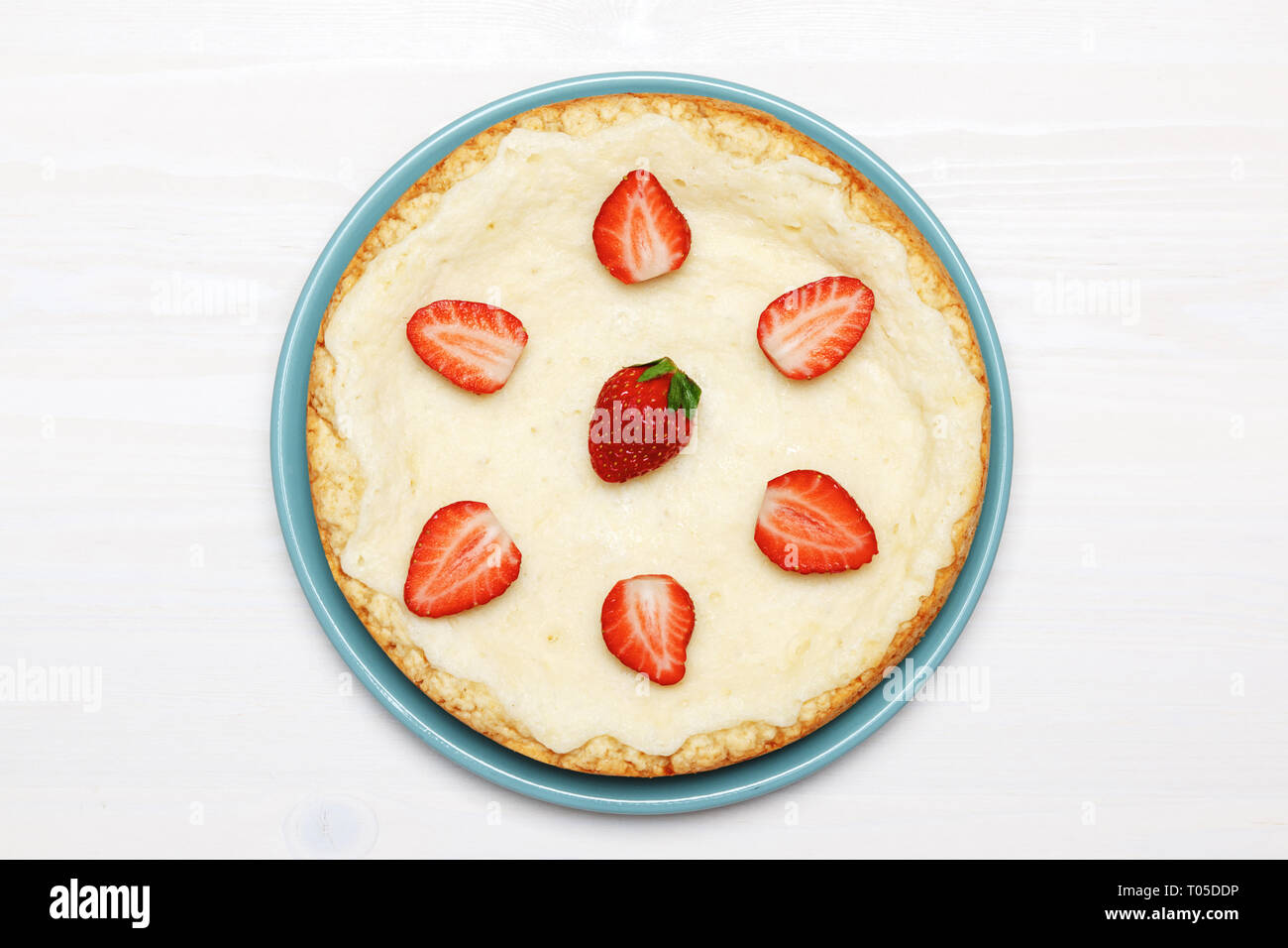 A whole classic cheesecake with strawberries on a white background. Top
