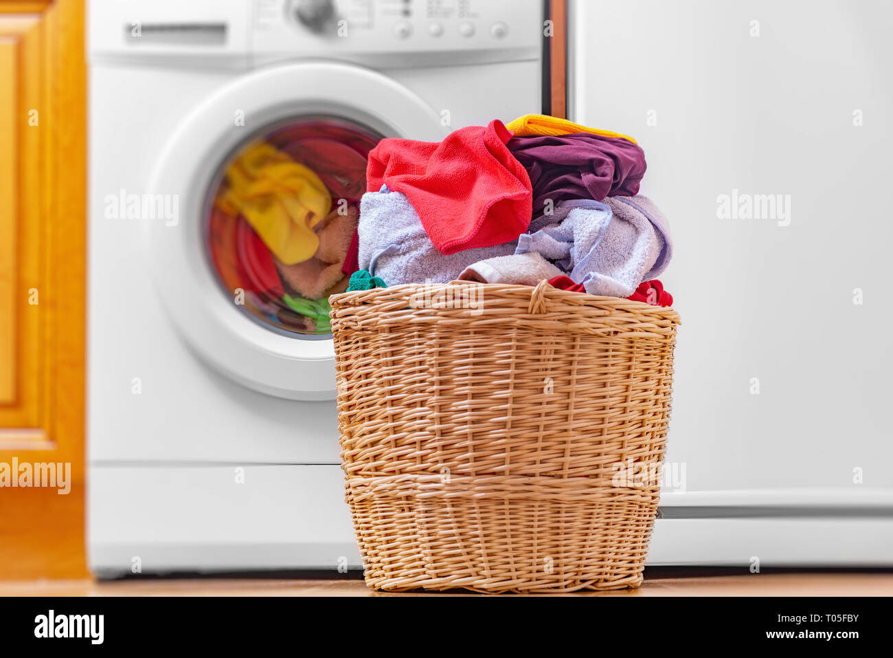 Washing machine and basket indoors. Stock Photo